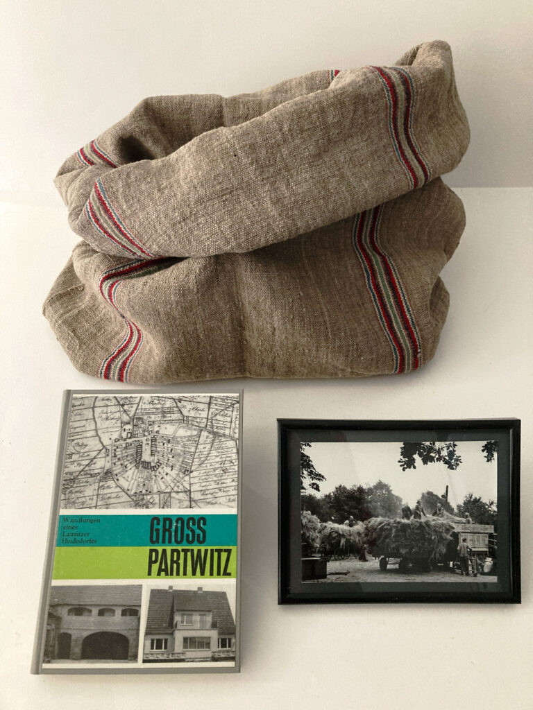 Objekte aus Groß Partwitz vor der Devastierung des Heidedorfes. Foto, Getreidesack und Publikation zum Wandlungsprozess.